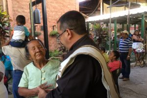 Fr. Alfredo Guillen, O. Carm., formator at Centro Xiberta and first Salvadoran to by ordained Carmelite, prays with a parishioner before celebrating the Sunday Mass